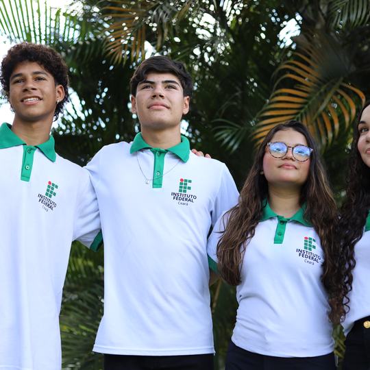 Estudantes do Instituto Federal do Ceará com a camisa branca e verde do uniforme, lado a lado em área arborizada